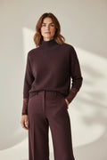 Plaza d'Amanté plum mock neck sweater featuring three-quarter sleeves with delicate lace cuffs worn with trousers.