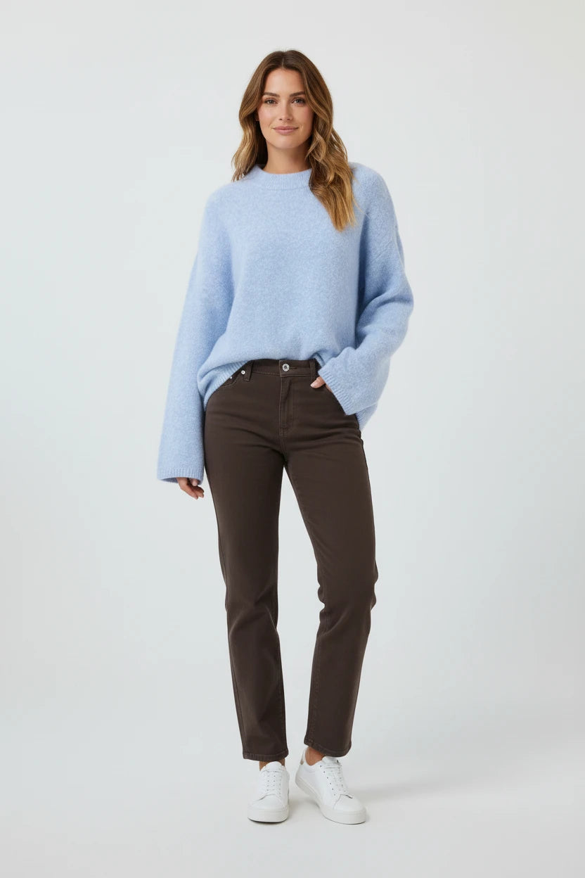 Plaza d'Amanté model wearing a fuzzy powder blue crewneck sweater with chocolate brown trousers and white sneakers.