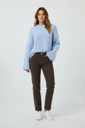 Plaza d'Amanté model wearing a fuzzy powder blue crewneck sweater with chocolate brown trousers and white sneakers.