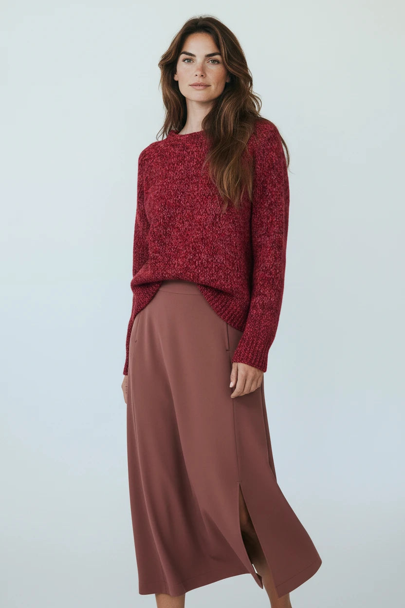 Plaza d'Amanté model wearing a deep red marled knit crewneck sweater and a clay-toned midi skirt with a side slit.