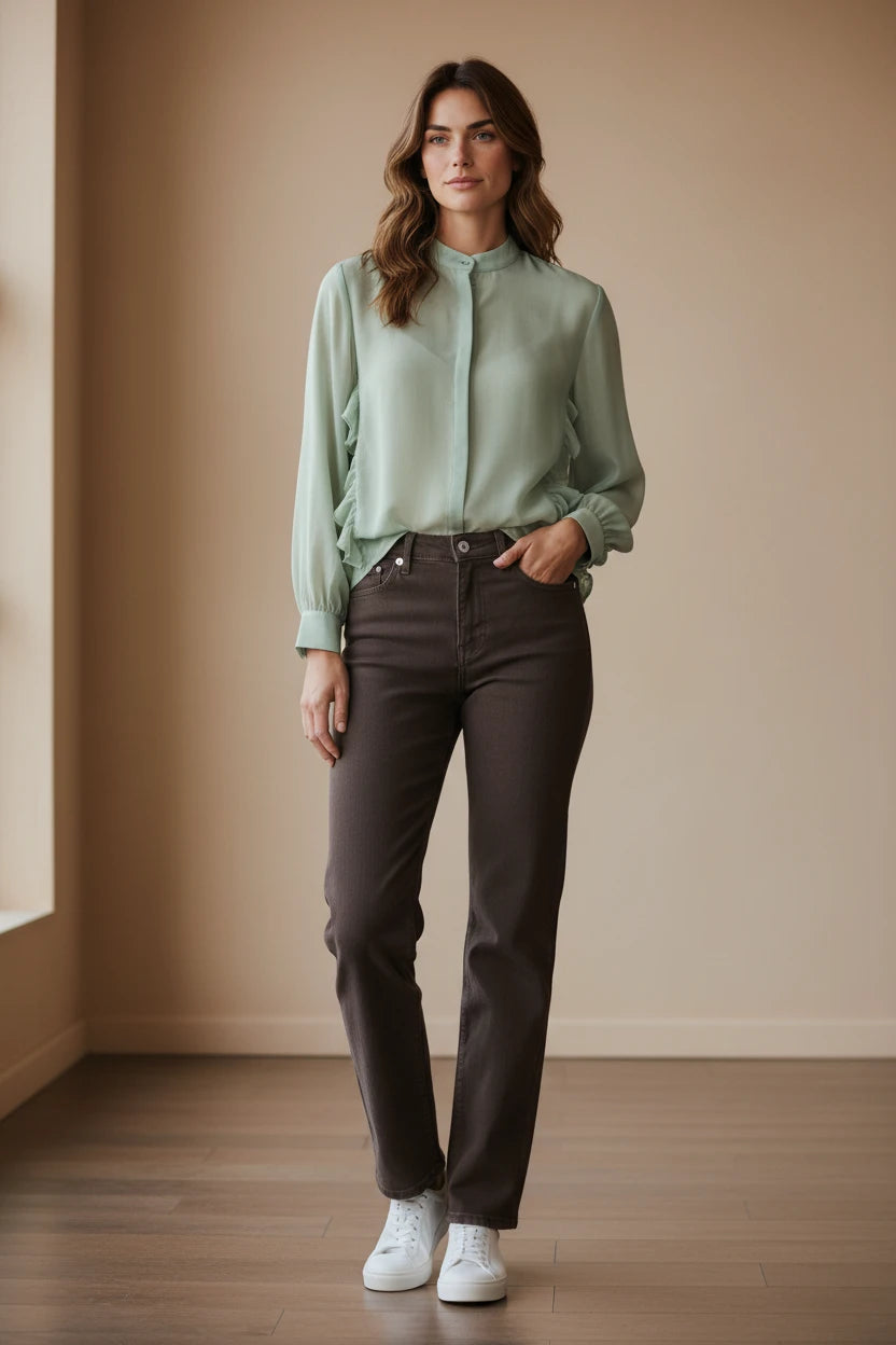 Plaza d'Amanté sage green long sleeve blouse with ruffle detail and dark brown straight-leg jeans on a female model