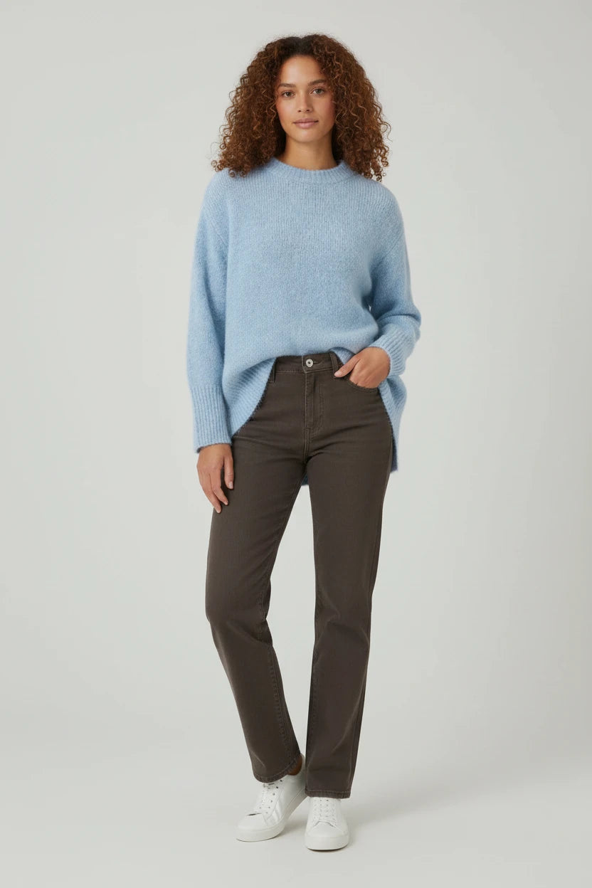 Plaza d'Amanté model wearing a sky-blue relaxed knit crewneck sweater with dark brown straight leg denim jeans