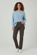 Plaza d'Amanté model wearing a sky-blue relaxed knit crewneck sweater with dark brown straight leg denim jeans