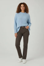 Plaza d'Amanté model wearing a sky-blue relaxed knit crewneck sweater with dark brown straight leg denim jeans