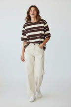 Plaza d'Amanté relaxed fit chocolate brown and cream striped cotton t-shirt worn by a smiling woman with cream jeans