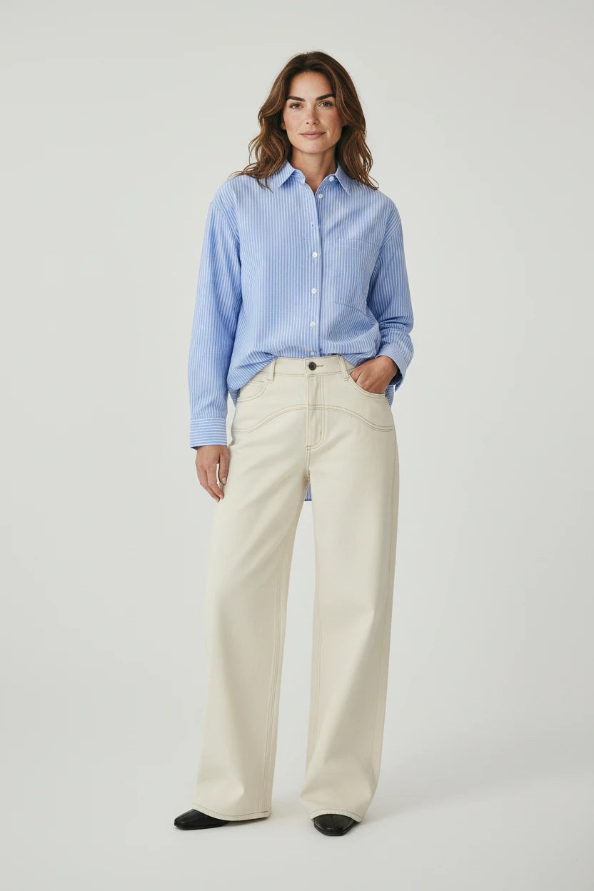 Plaza d'Amanté model wearing a blue and white striped button-down shirt with cream high-waisted wide-leg trousers.