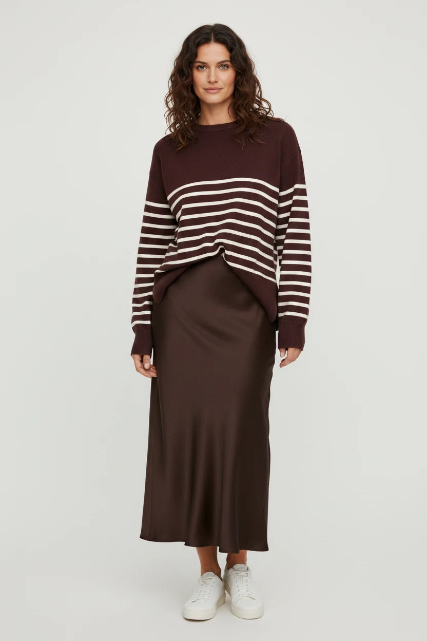Plaza d'Amanté model wearing a brown striped knit sweater and a matching satin midi skirt with white sneakers.